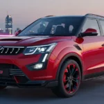 Mahindra XUV 3XO 2026 in sporty Magma Red finish parked on an urban rooftop at sunset, featuring gloss black alloy wheels and LED lighting